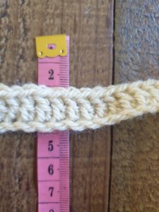 A photo of one row of double crochet next to a tape measure, showing its height of 2 cm