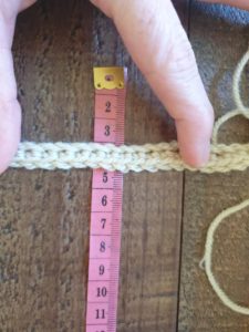 A photo of one row of single crochet next to a tape measure, showing its height of 1 cm