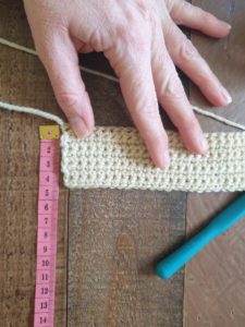 A photo eight rows of single crochet next to a tape measure, showing its height of 4 cm
