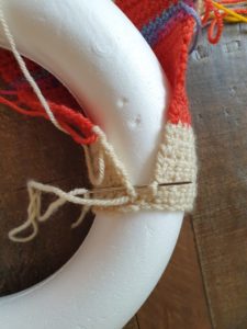 A photo showing the flat piece of crochet being wrapped around the wreath and stitched together so that it covers the wreath