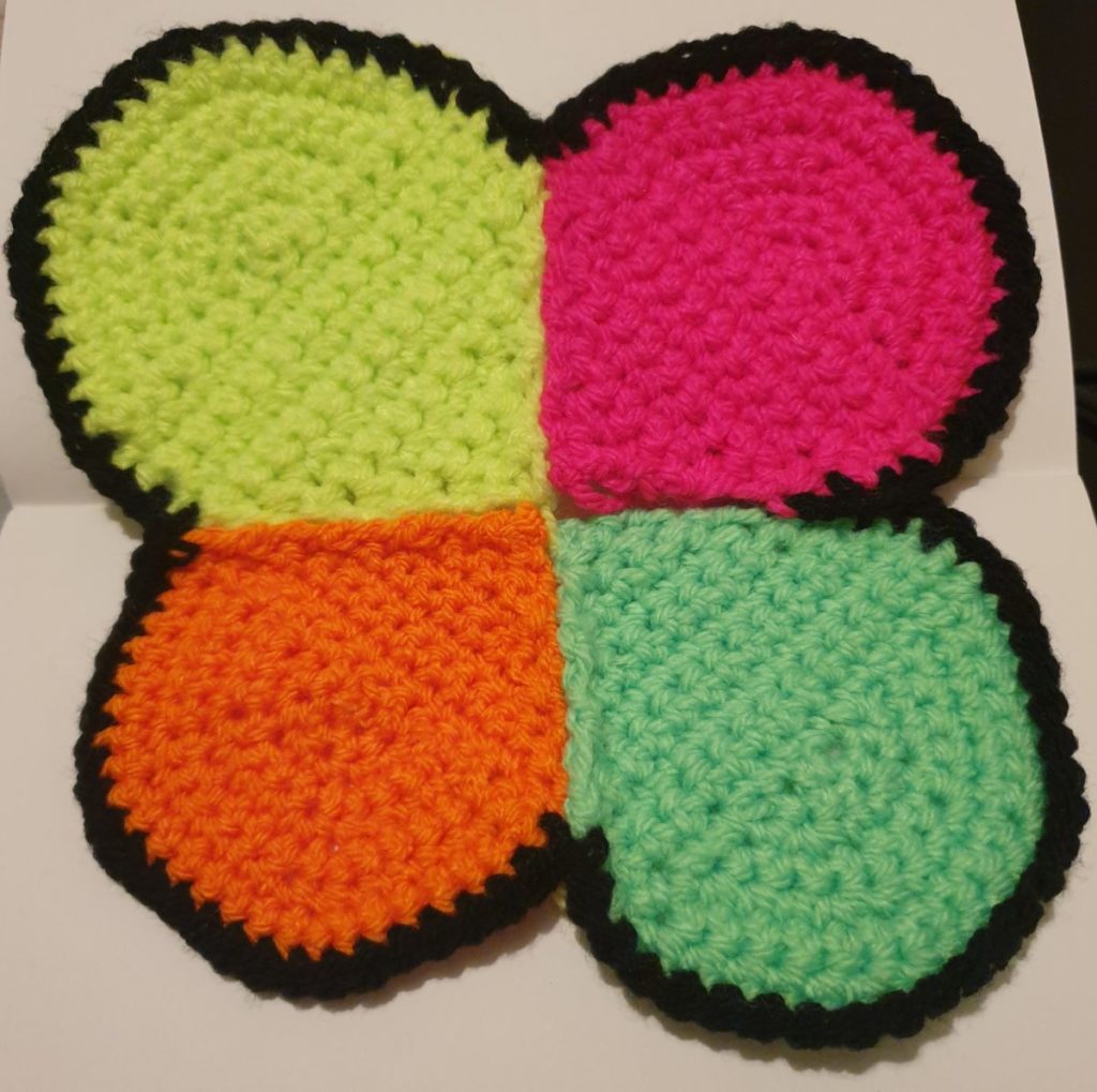 Crochet representation of Deinococcus radiodurans as four neon coloured circles joined together in a tetrad