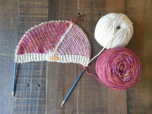 Photo showing a semicircle shaped piece of knitting in cream and red