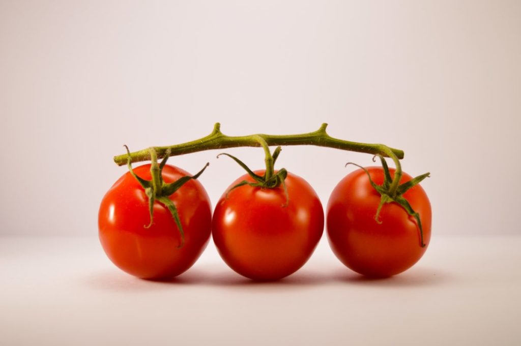 Three tomatoes on a vine.