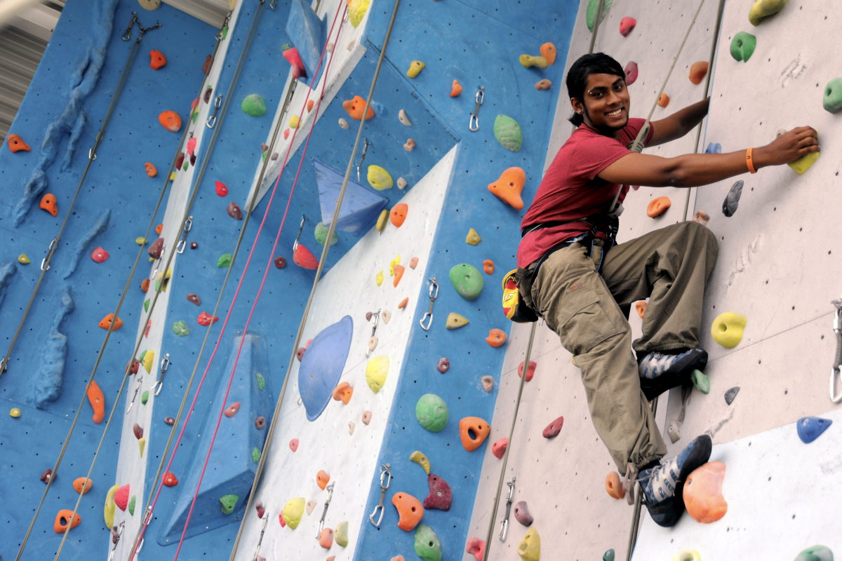 A student scaling the climbing wall