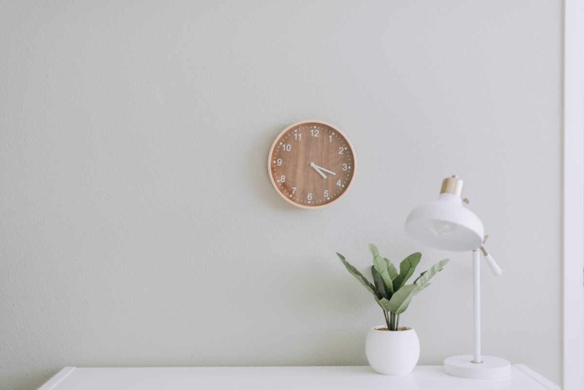 Tidy room with only a clock, lamp and plant on display