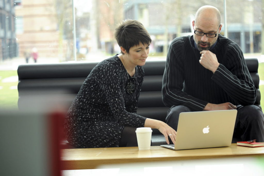 Two people discussing work displayed on a laptop