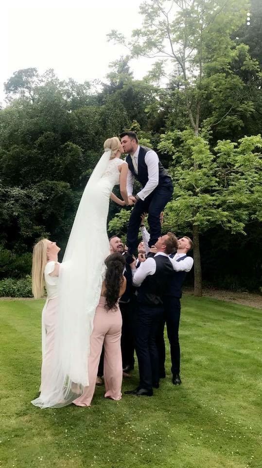 Laura and Lewis being lifted for a kiss at their wedding