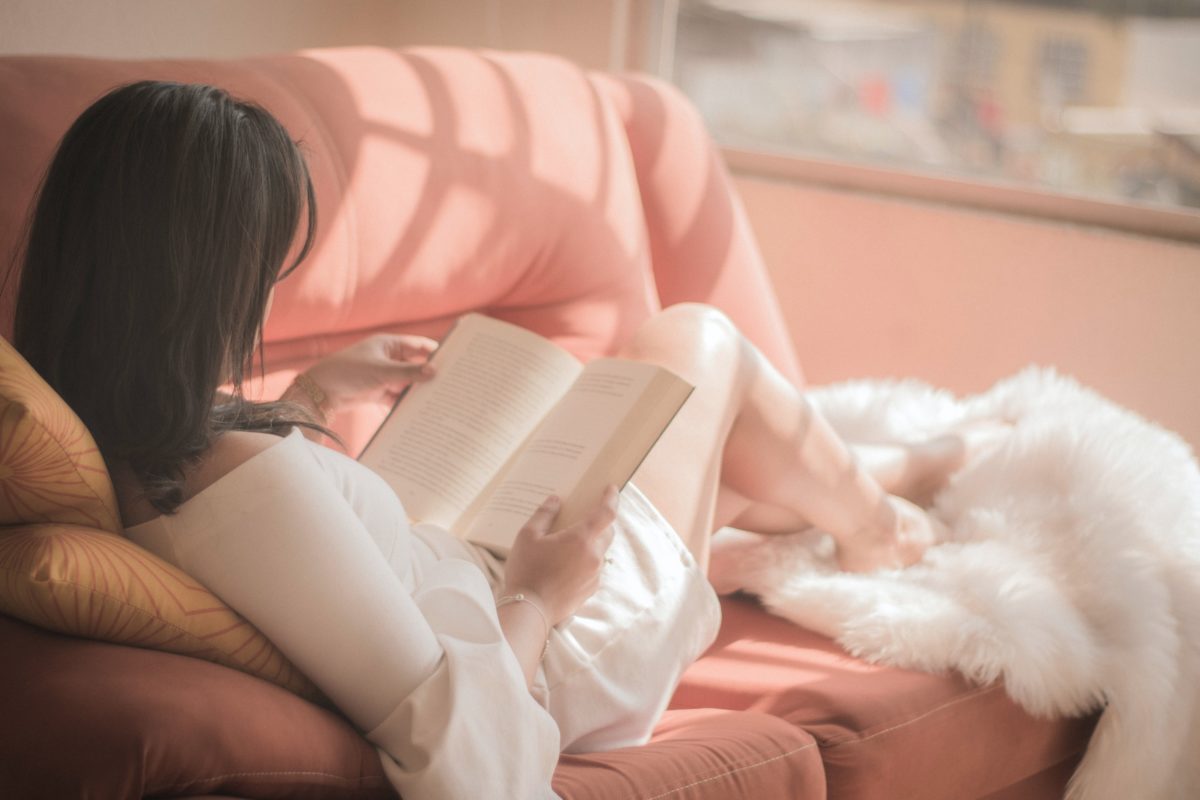 Image of woman sitting on a couch reading a book