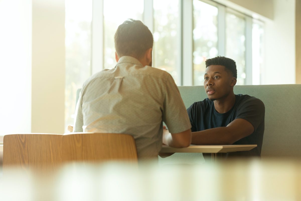 Image of young man having a conversation with someone at a table