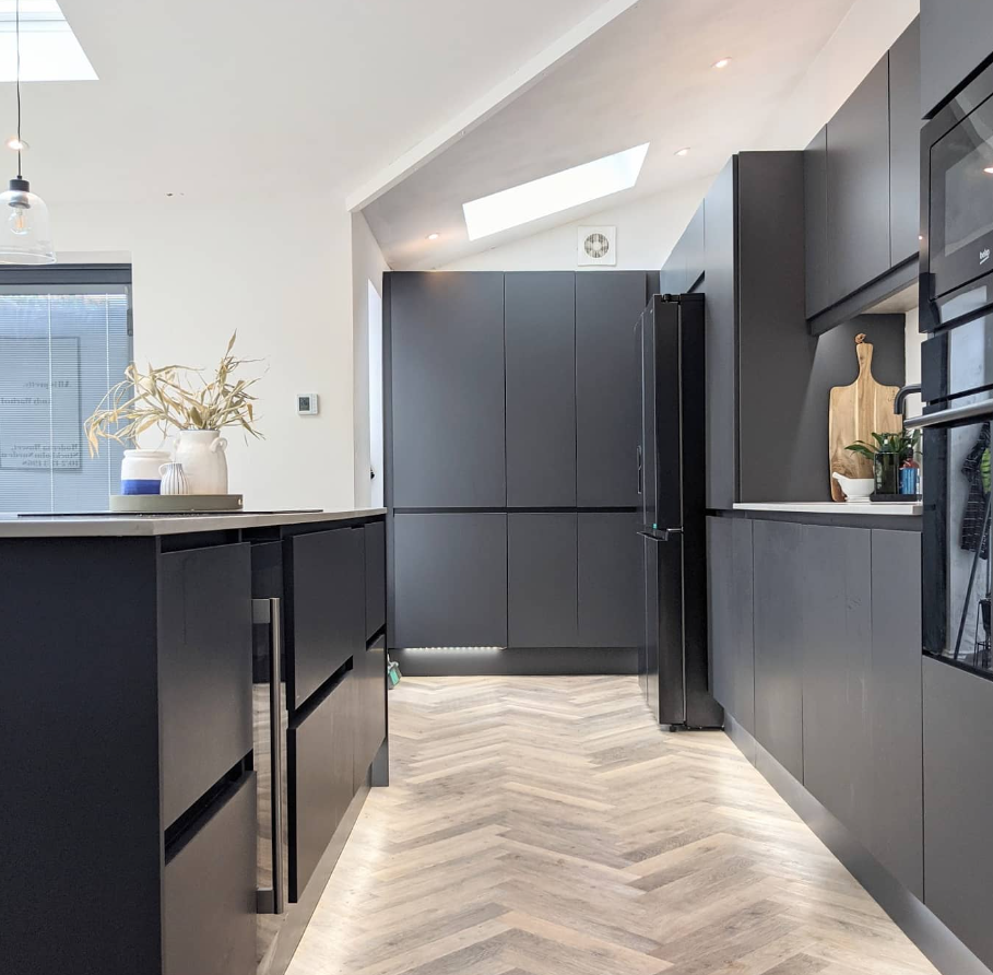 Kitchen with black flat-panel cabinets and light parquet flooring.