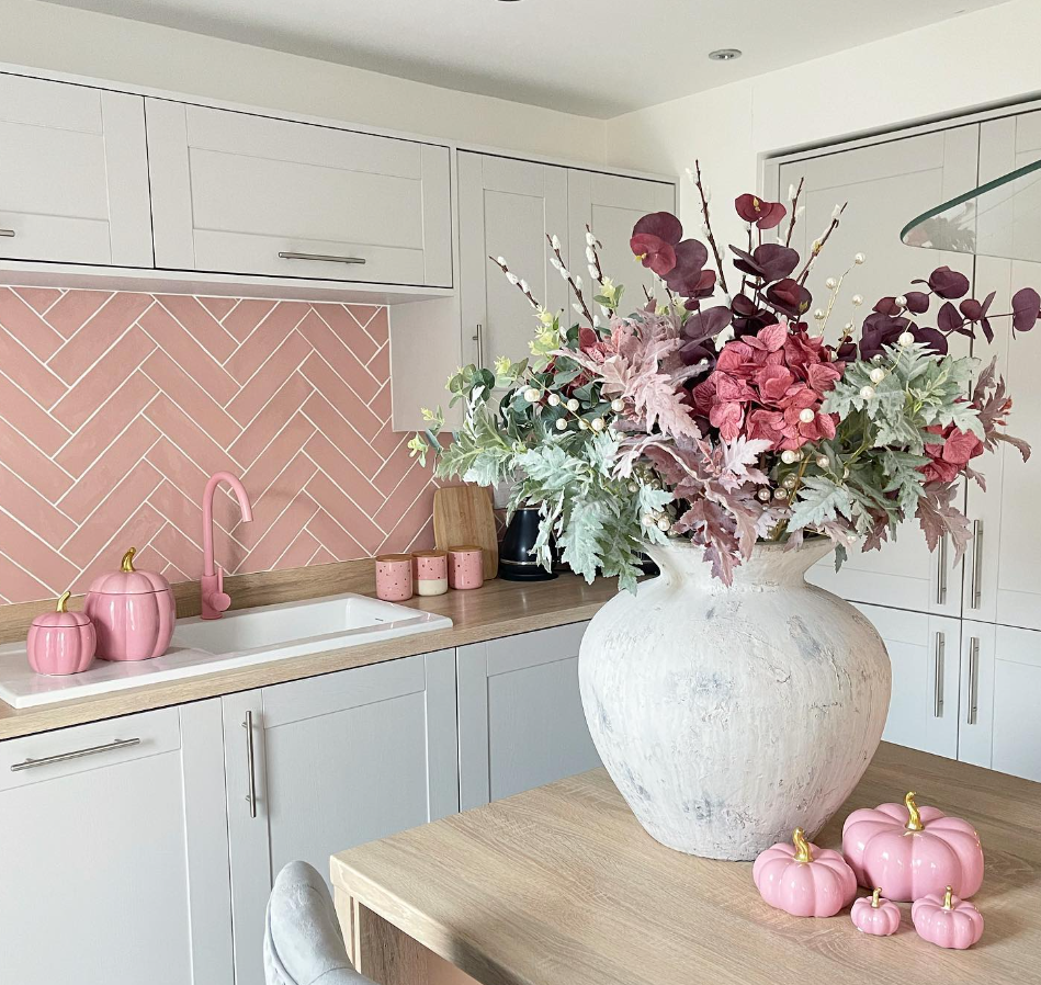 White kitchen featuring a pink tiled backsplash and pink kitchen tap. 