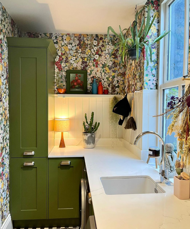 Stylish utility room with bold floral wallpaper and green cabinetry.