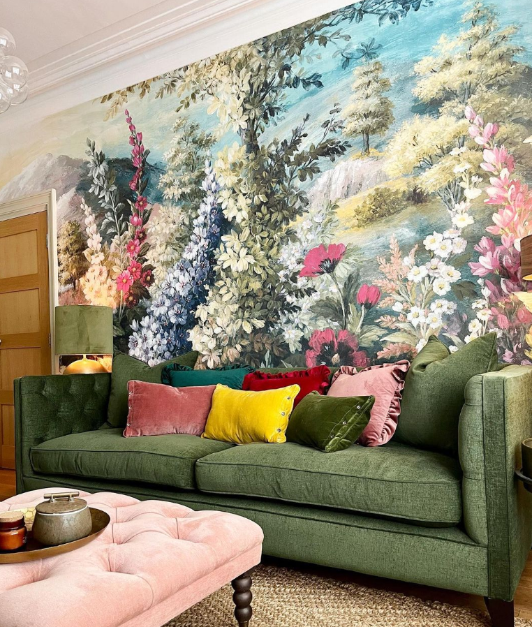 Floral wall mural behind a green velvet sofa.