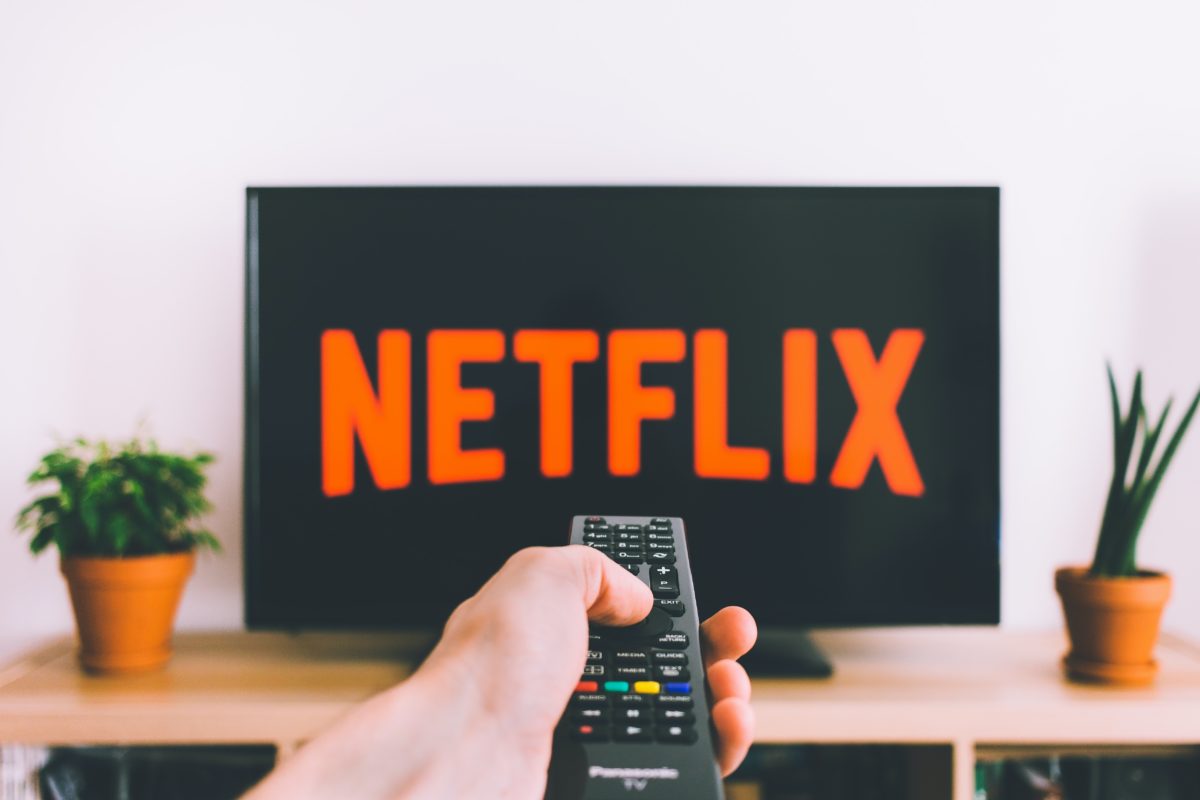 Person pointing remote at television on Netflix