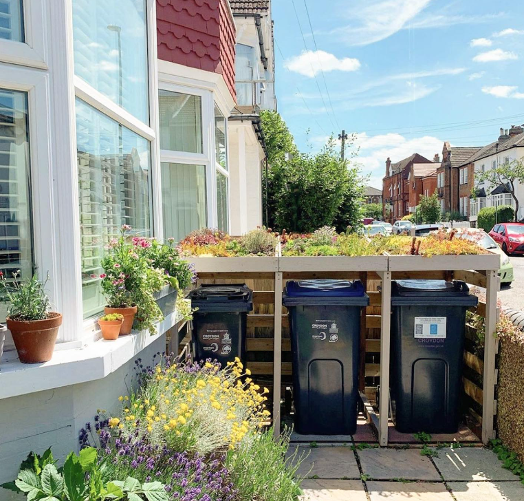 Image shows three wheely bins in a bin shed, topped with a living roof.
