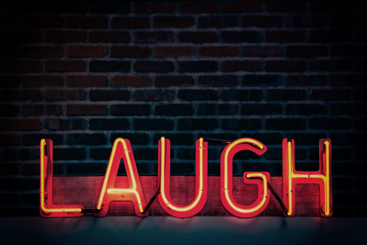 Red neon sign saying 'laugh'