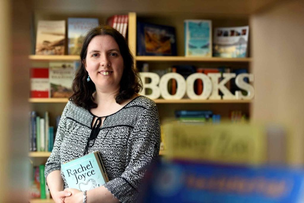 Jenna Warren pictured holding a book inside her book shop.