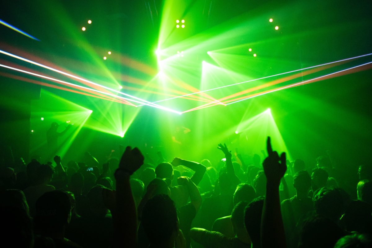 People dancing to music under green laser lights