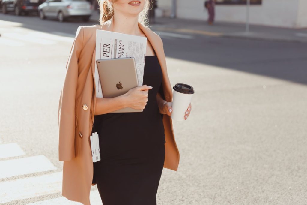 Image shows a young woman holding a notebook and iPad.