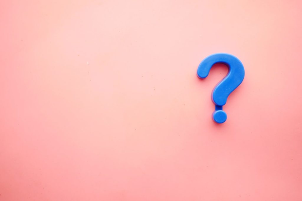 Blue question mark on a pale pink background.