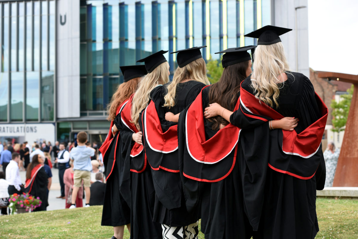 A group of graduates showing the back of their academic gowns