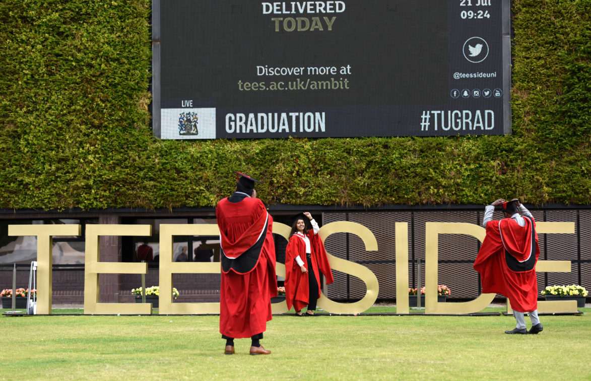 Master's graduates taking photos with the large Teesside letters