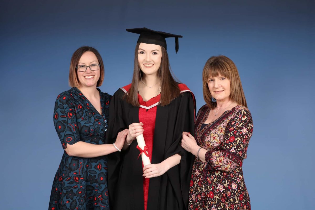A graduate holding a scroll and smiling with her family