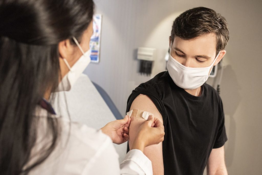 A nurse putting a plaster on a person's arm after they received a flu jab