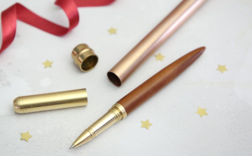Christmas pen on a table with red ribbon and gold stars