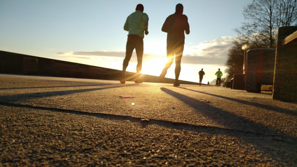 Image shows silhouettes of two people running at dusk.