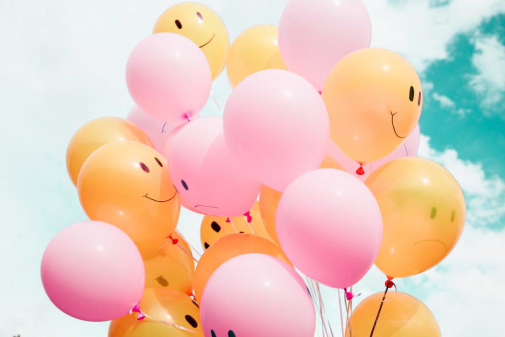 Bunch of pink and orange balloons with smiley faces.