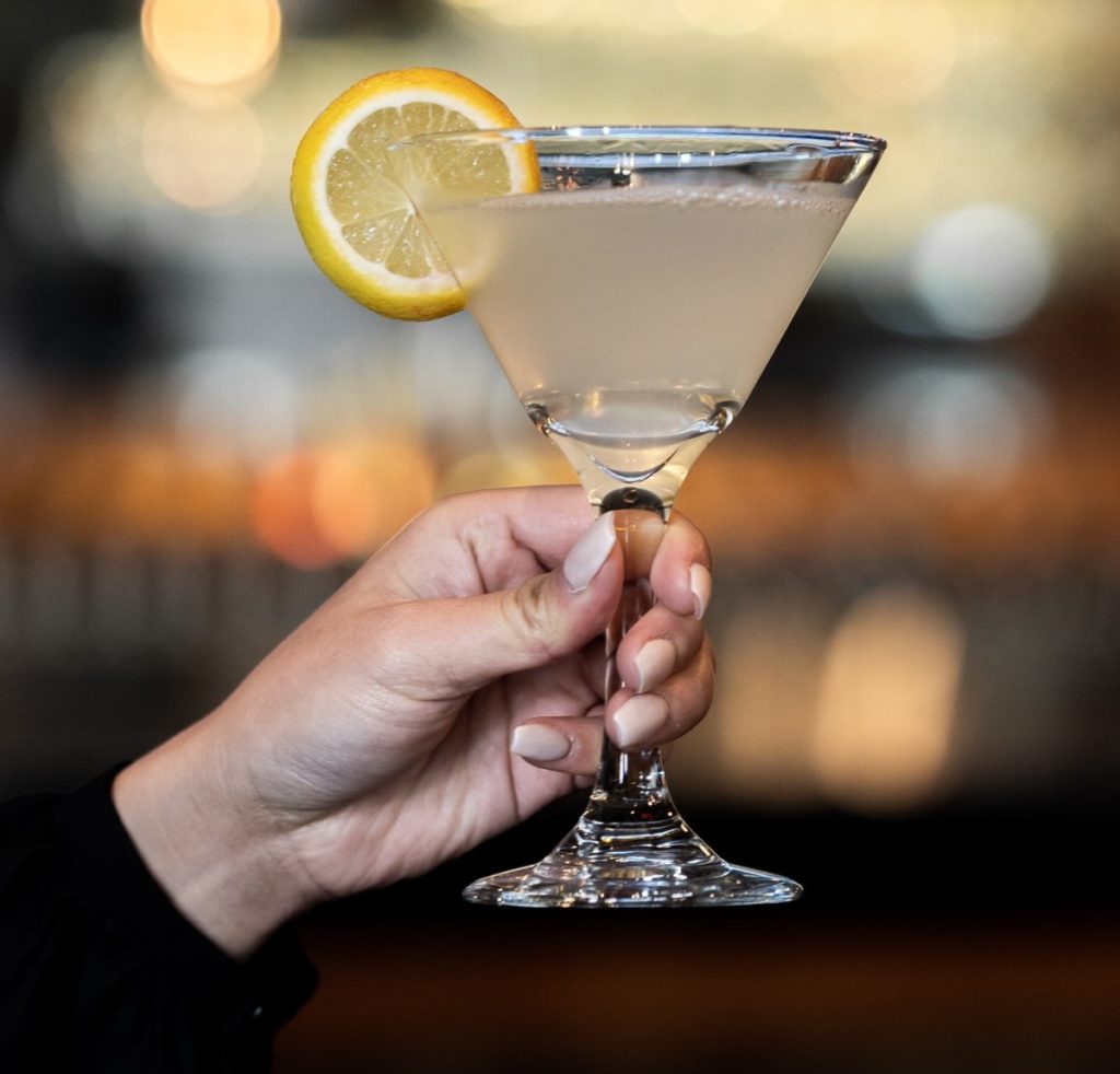 Person holding a lemon martini up in a cocktail glass.