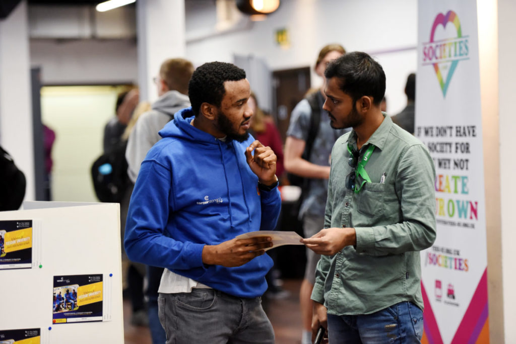 Two students talking at the societies fair