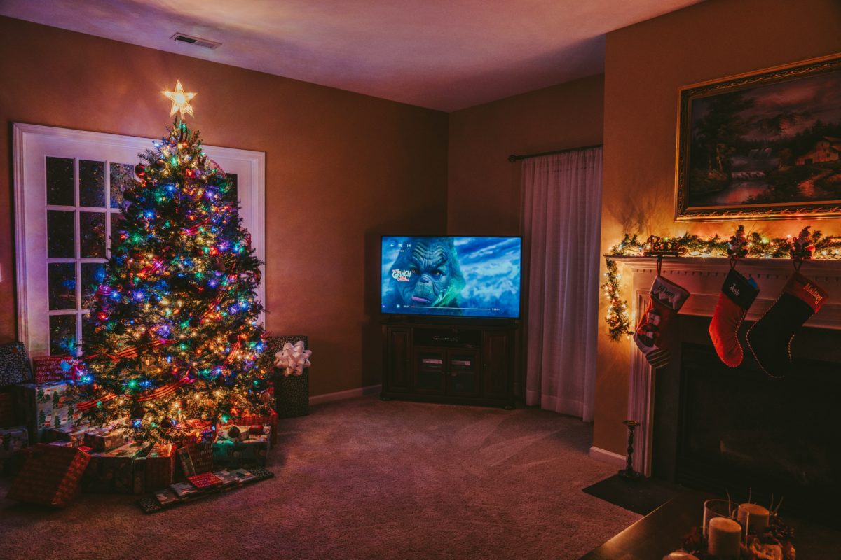 A living room decorated for Christmas, with a tree and stockings on the fireplace. How the Grinch Stole Christmas is playing on the television.