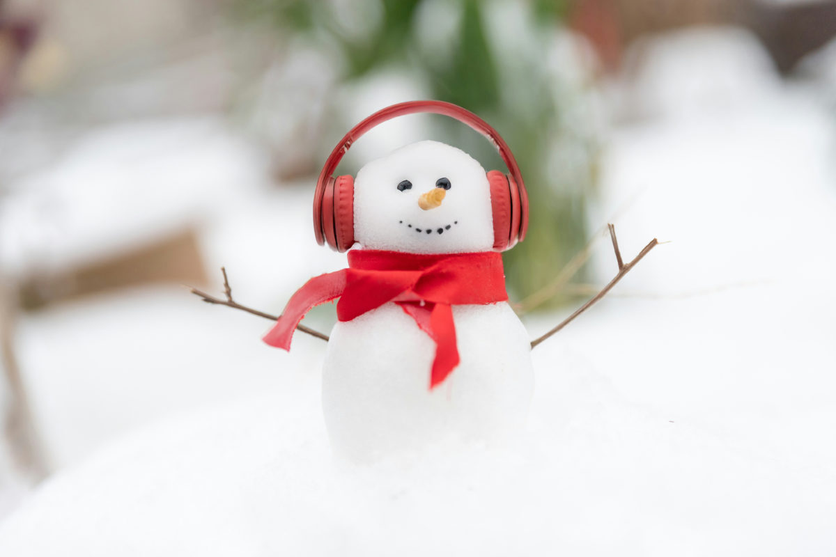 A snowman wearing red, wireless headphones and a matching scarf