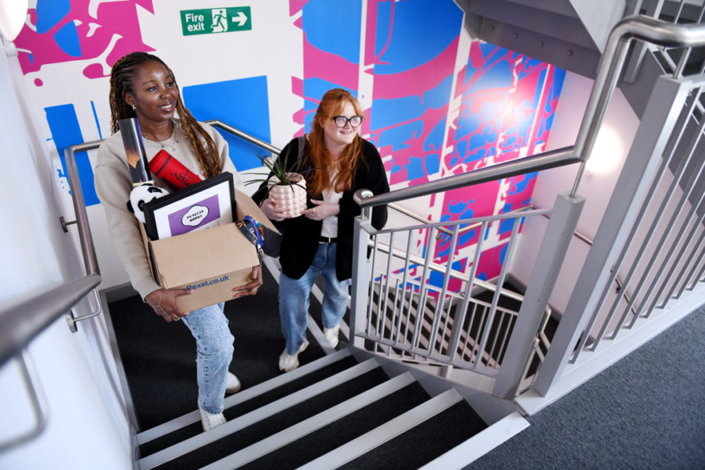 Students carrying moving boxes upstairs